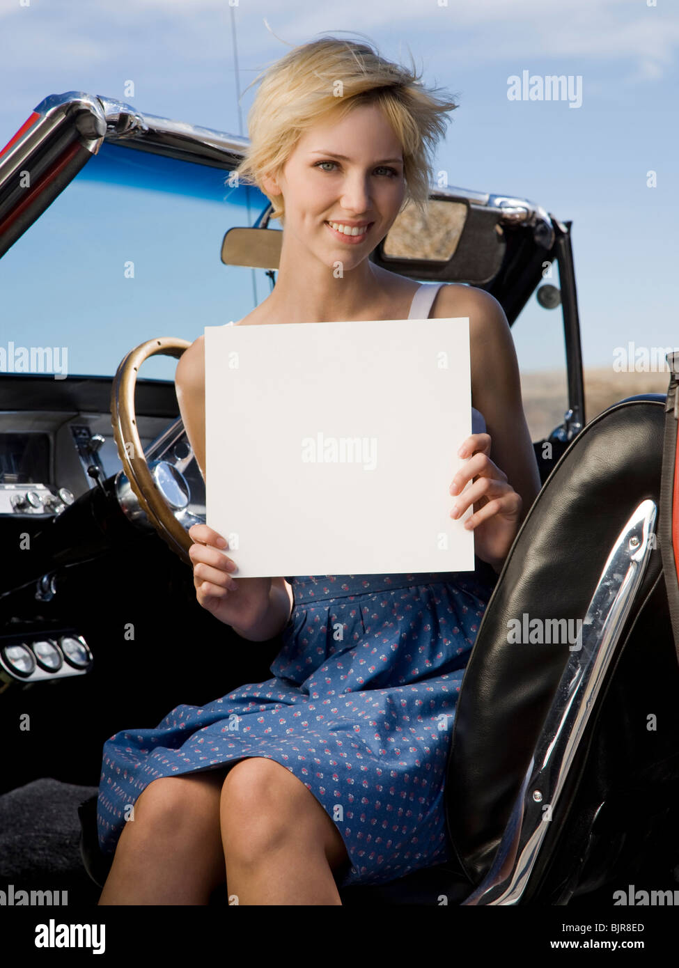 woman in a car with a blank sign Stock Photo
