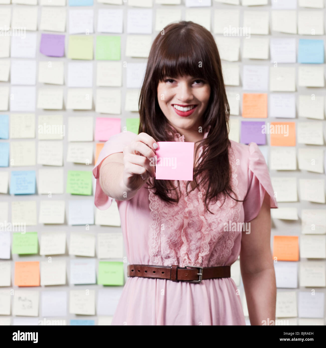 Portrait of young woman holding adhesive note Stock Photo