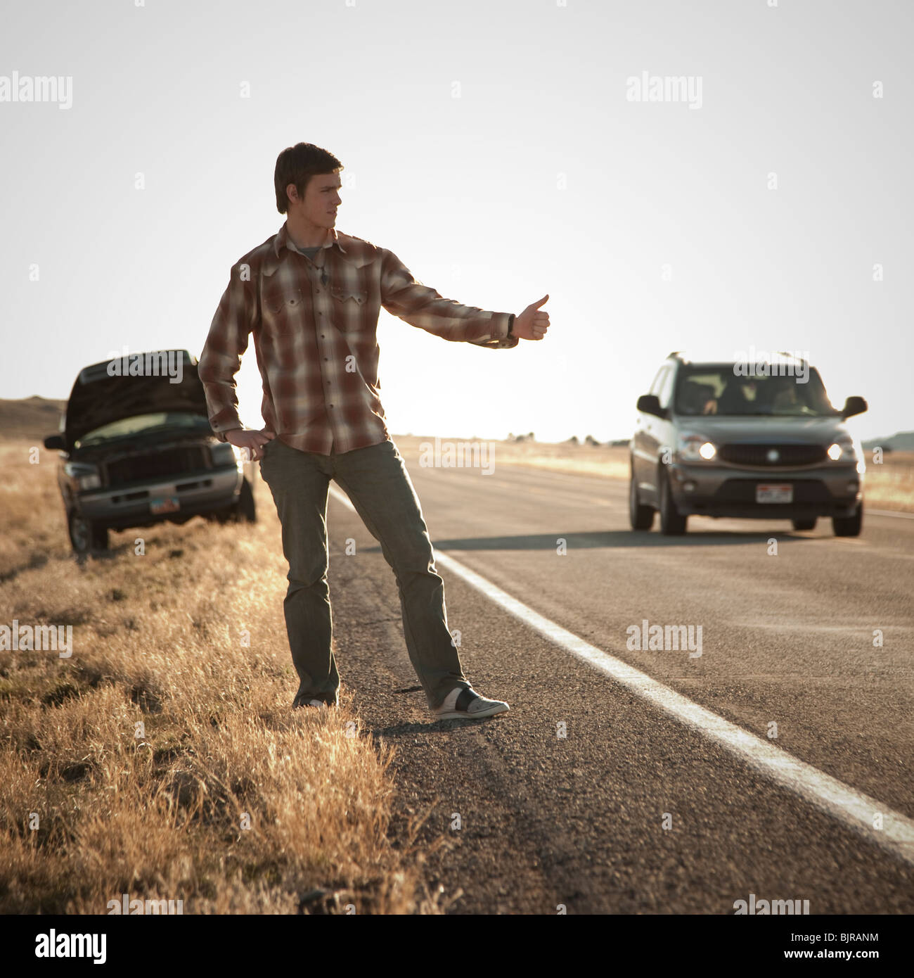 USA, Utah, man hailing on roadside, broken car in background Stock Photo