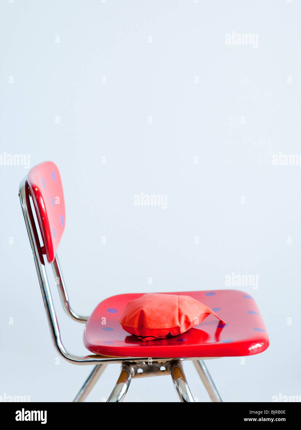 Red whoopie cushion on red spotted chair, studio shot Stock Photo