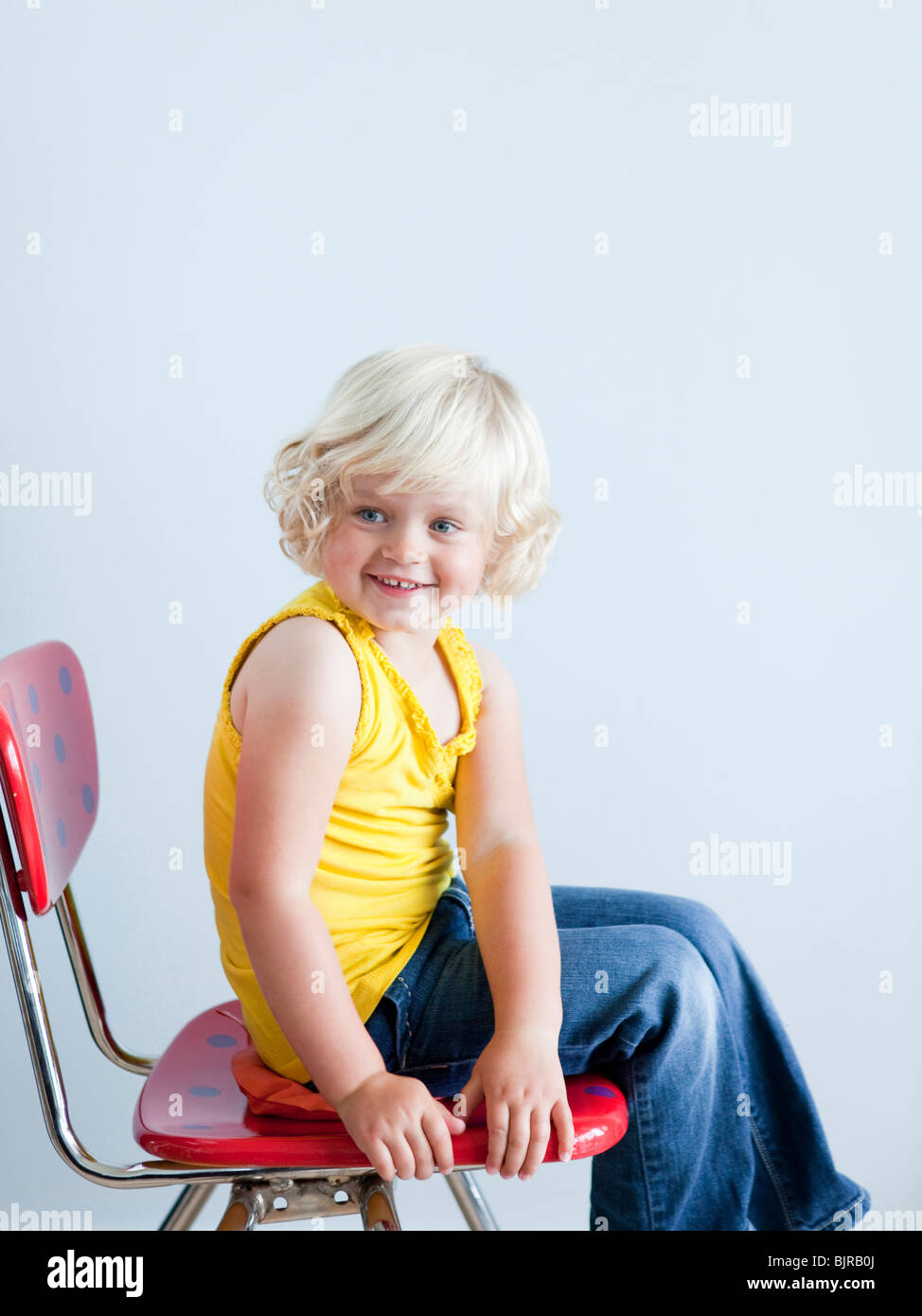 Girl (2-3) sitting on whoopie cushion, smiling, studio shot Stock Photo