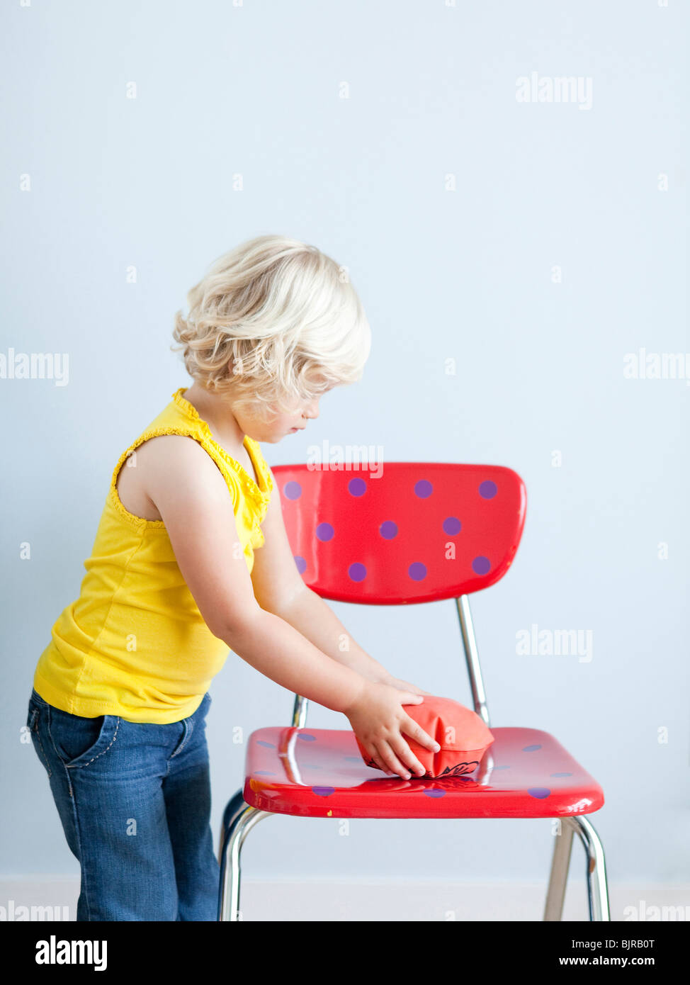 Girl (2-3) putting whoopie cushion on chair, studio shot Stock Photo