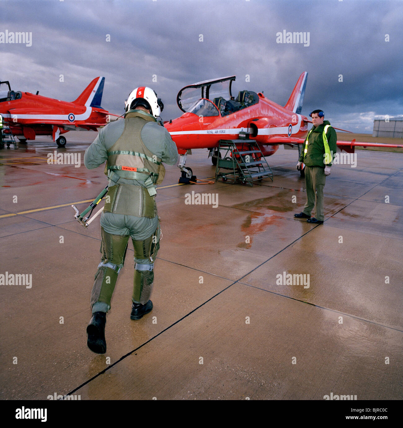 Squadron Leader Duncan Mason strides out to his waiting Hawk jet for more Red Arrows winter training from RAF Scampton. Stock Photo