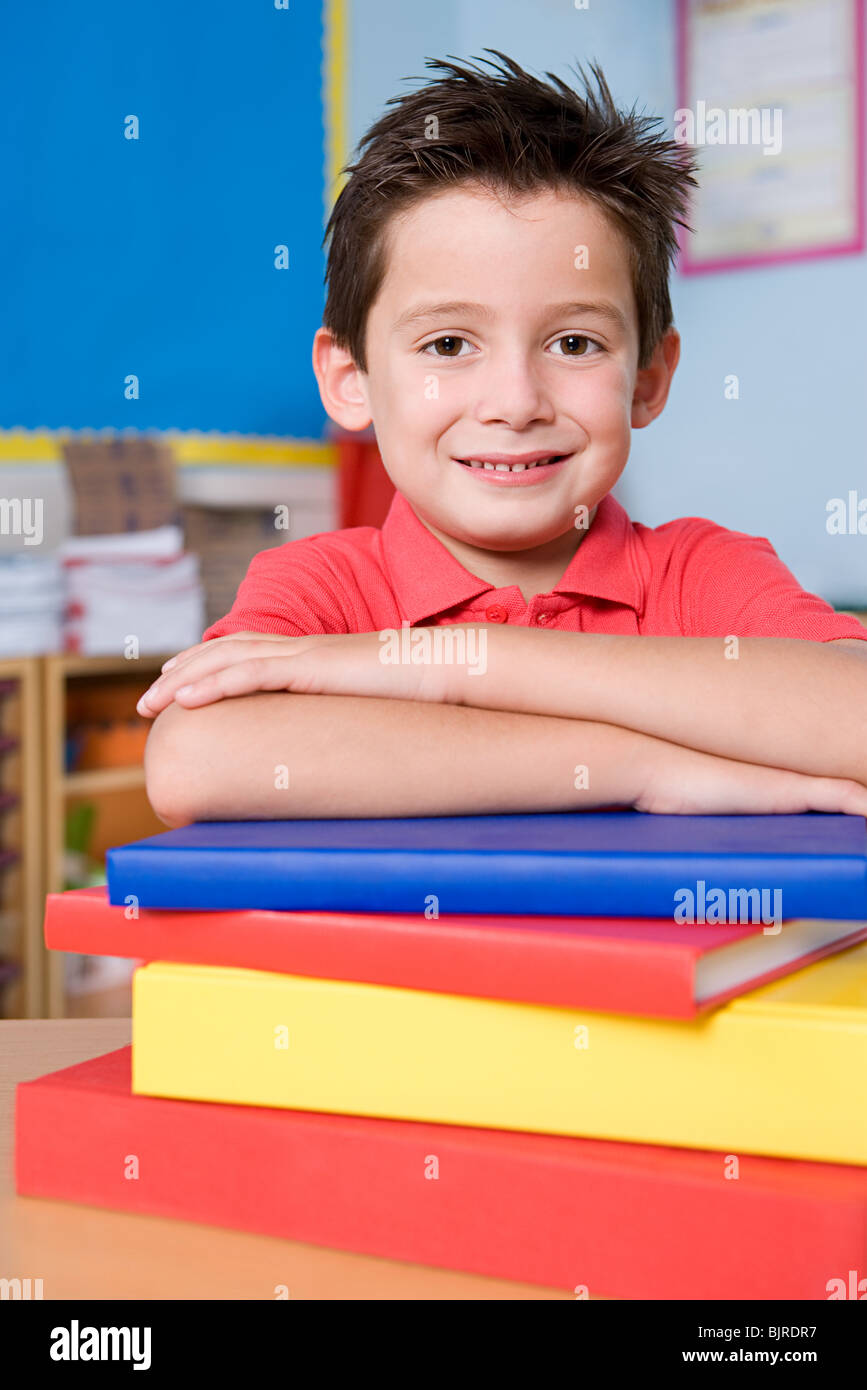 Boy leaning on stack of books Stock Photo - Alamy
