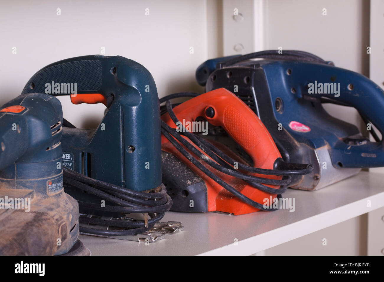 Various potable power tools line the shelves of a cupboard in a workshop. Stock Photo