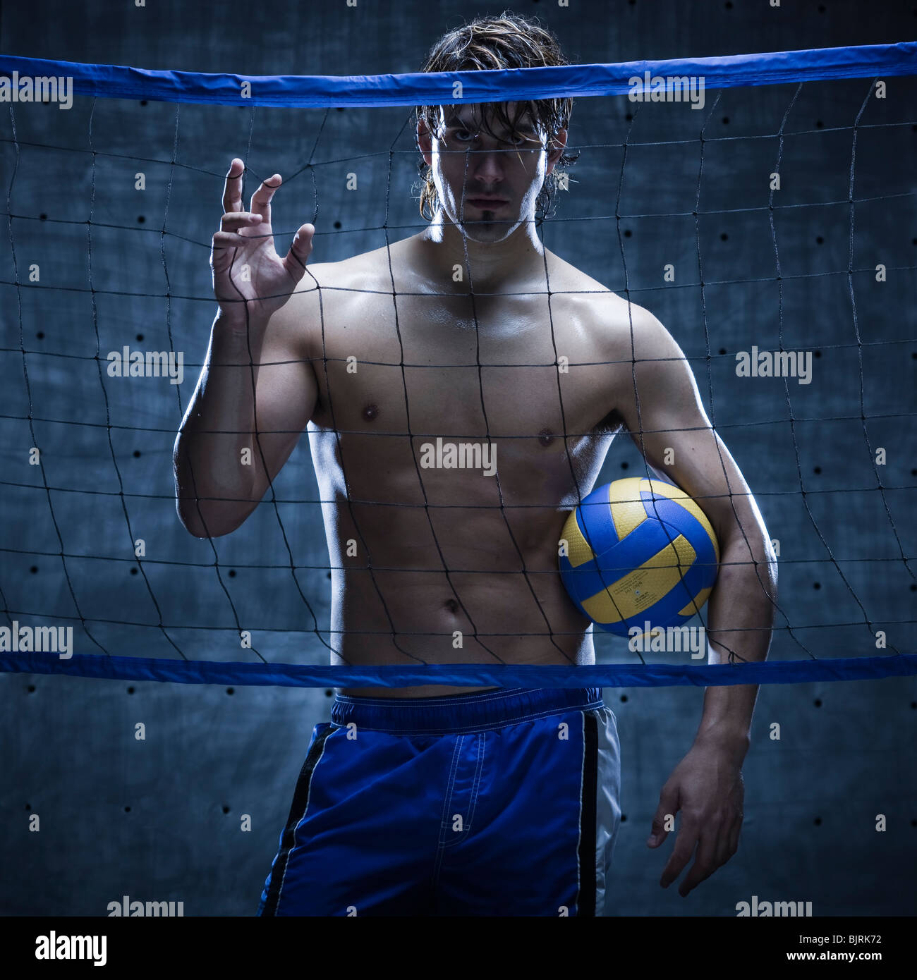 Studio shot of volleyball player standing behind net Stock Photo Alamy
