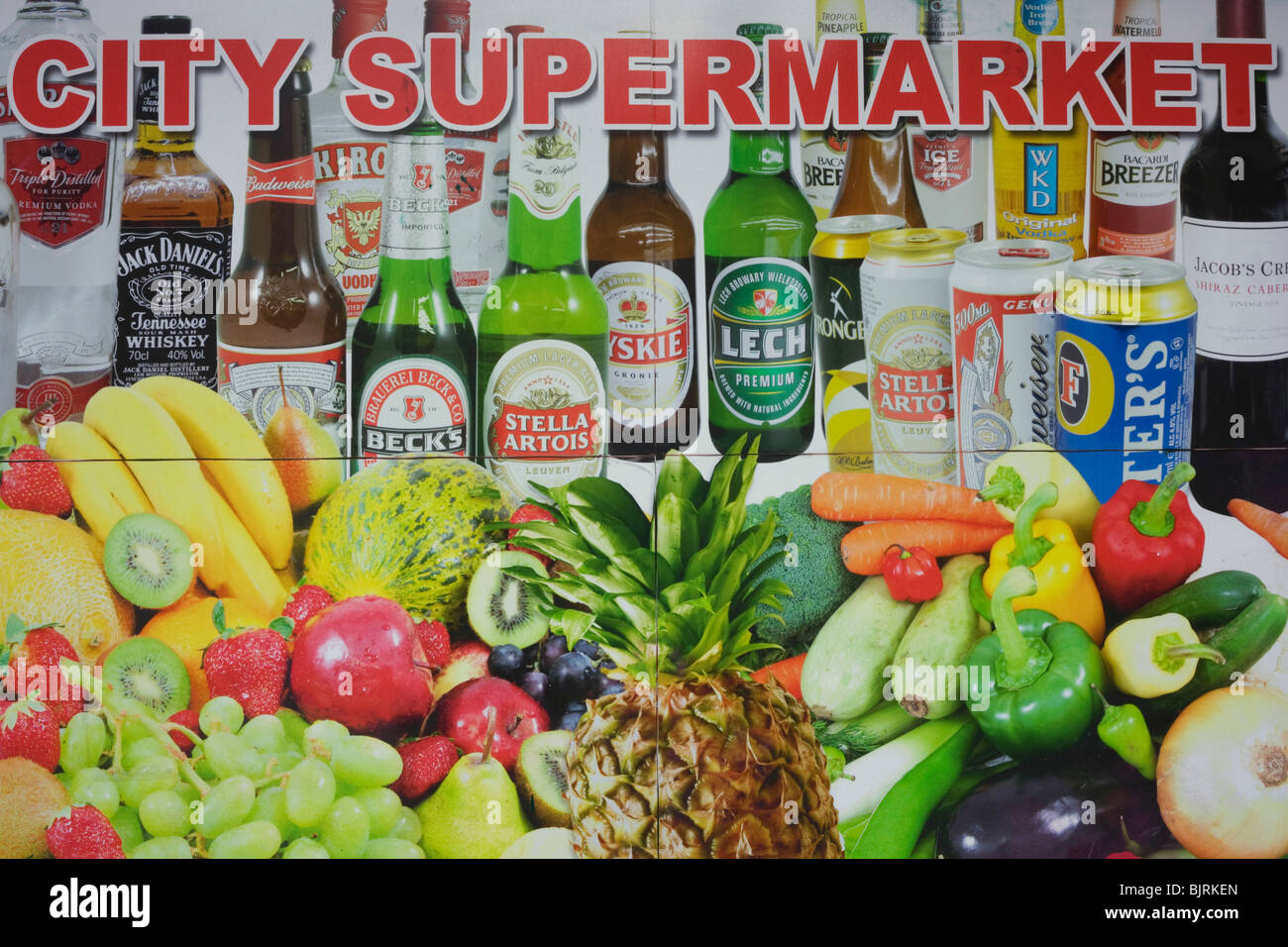 A city supermarket advertises bottles and cans of lager beers and fresh fruit and vegetables. Stock Photo
