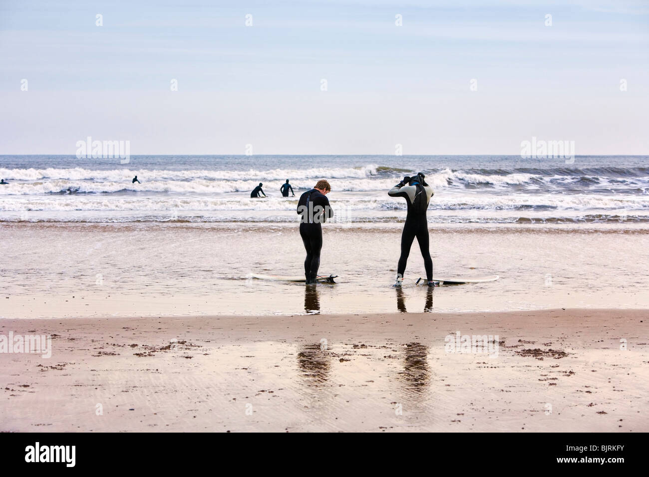 Surfers on beach in winter time England UK Stock Photo