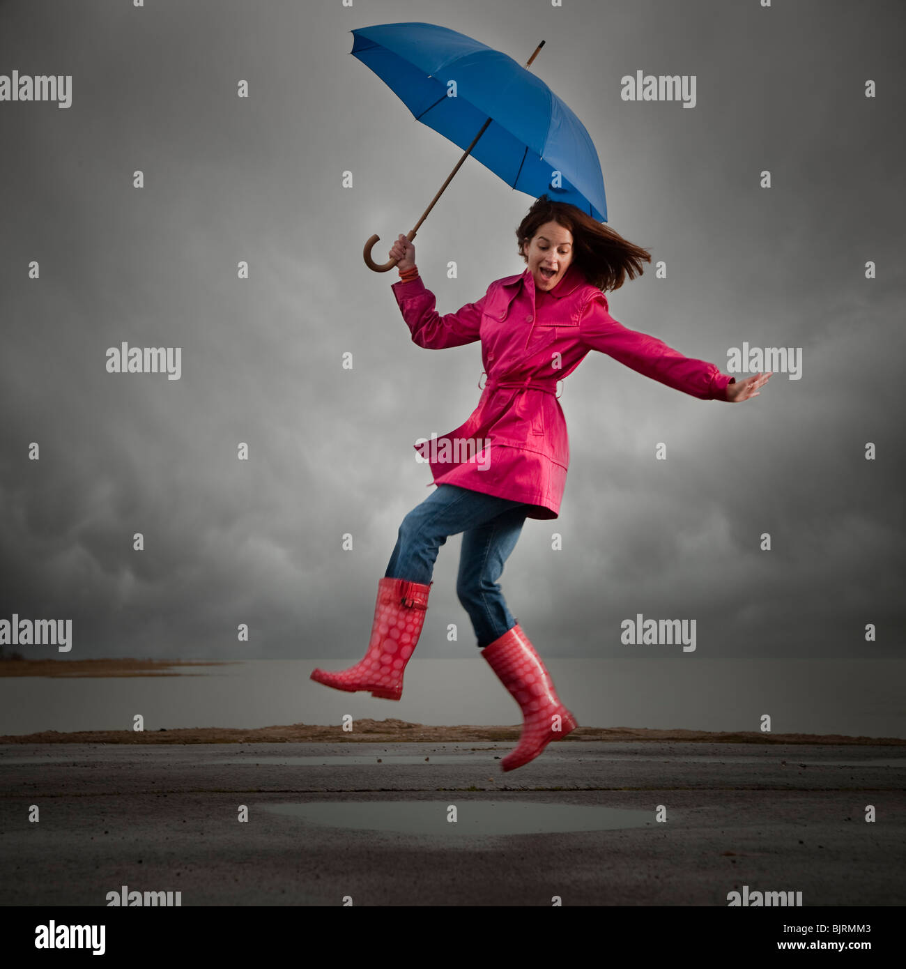 USA, Utah, Orem, woman with umbrella jumping under overcast sky Stock Photo