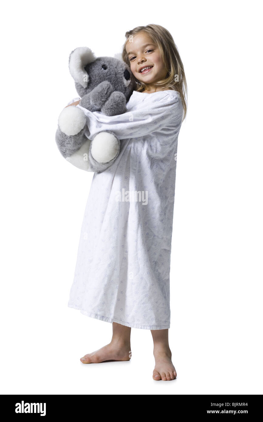 Young girl in nightie holding koala bear plush toy Stock Photo