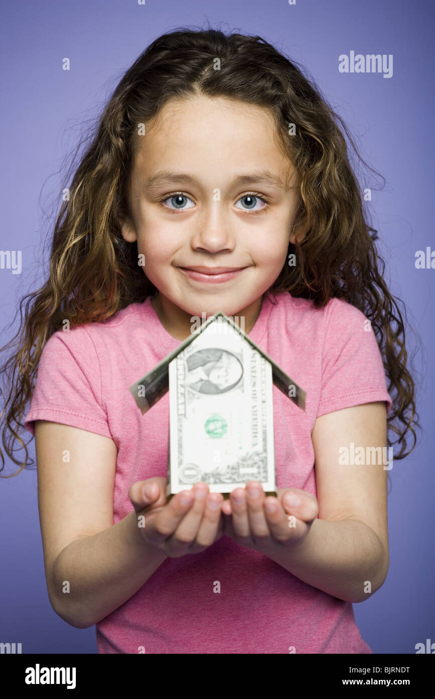Young girl with a little house made of banknotes Stock Photo