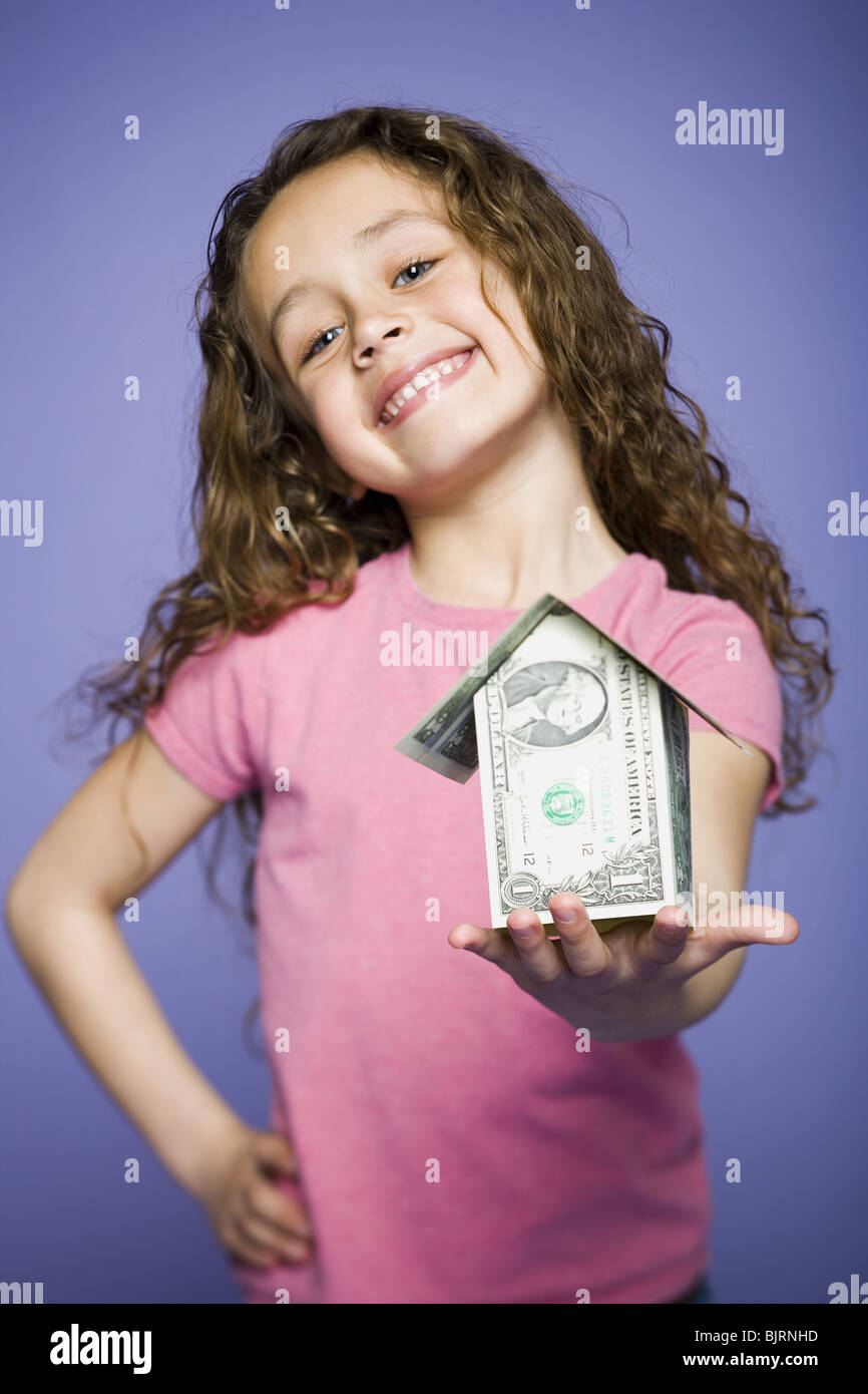Young girl with a little house made of banknotes Stock Photo