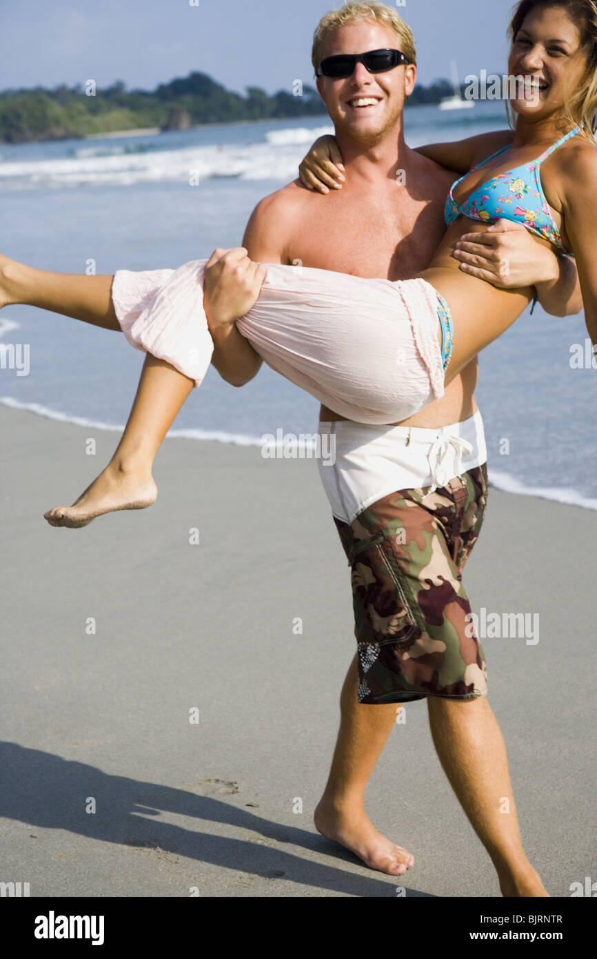 Man carrying girlfriend on beach Stock Photo