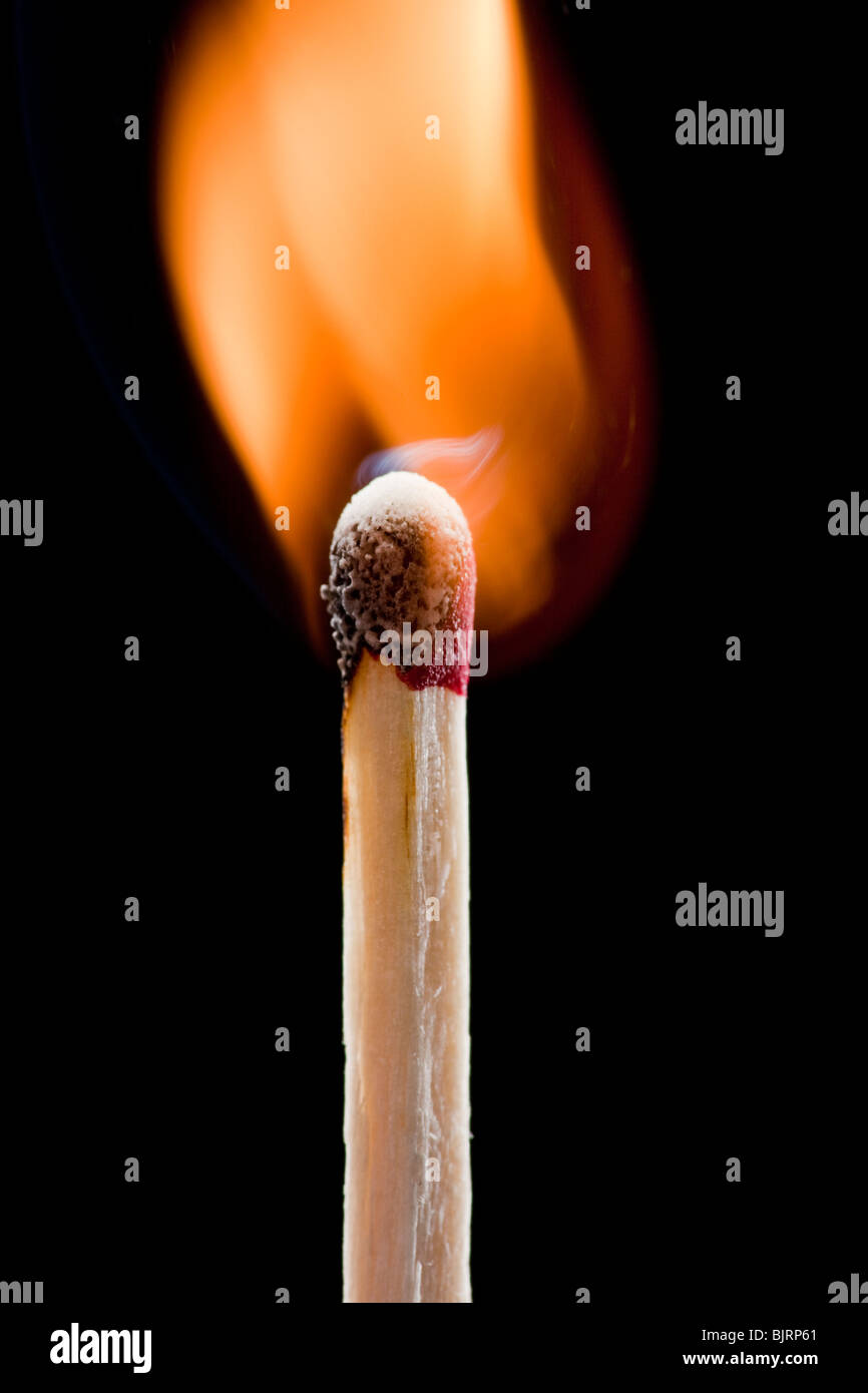 Burning match against black background Stock Photo