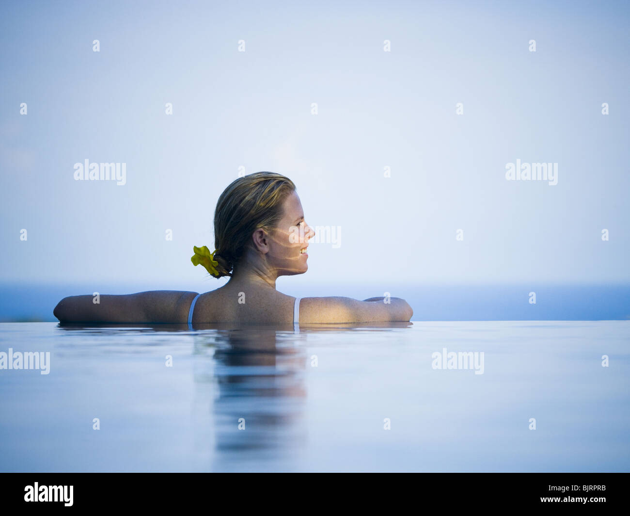Woman relaxing in infinity pool Stock Photo