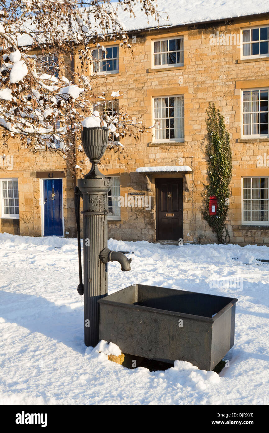 Winter snow on the old water pump and Cotswold stone houses in the High Street, Chipping Campden, Gloucestershire Stock Photo