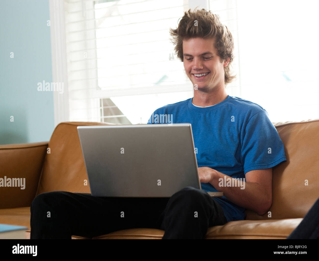 USA, Utah, Provo, young man sitting on sofa and using laptop Stock Photo