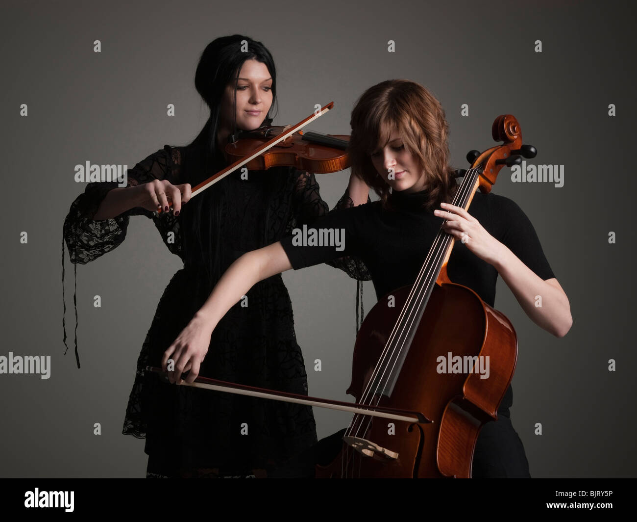 Two young women playing string instruments Stock Photo
