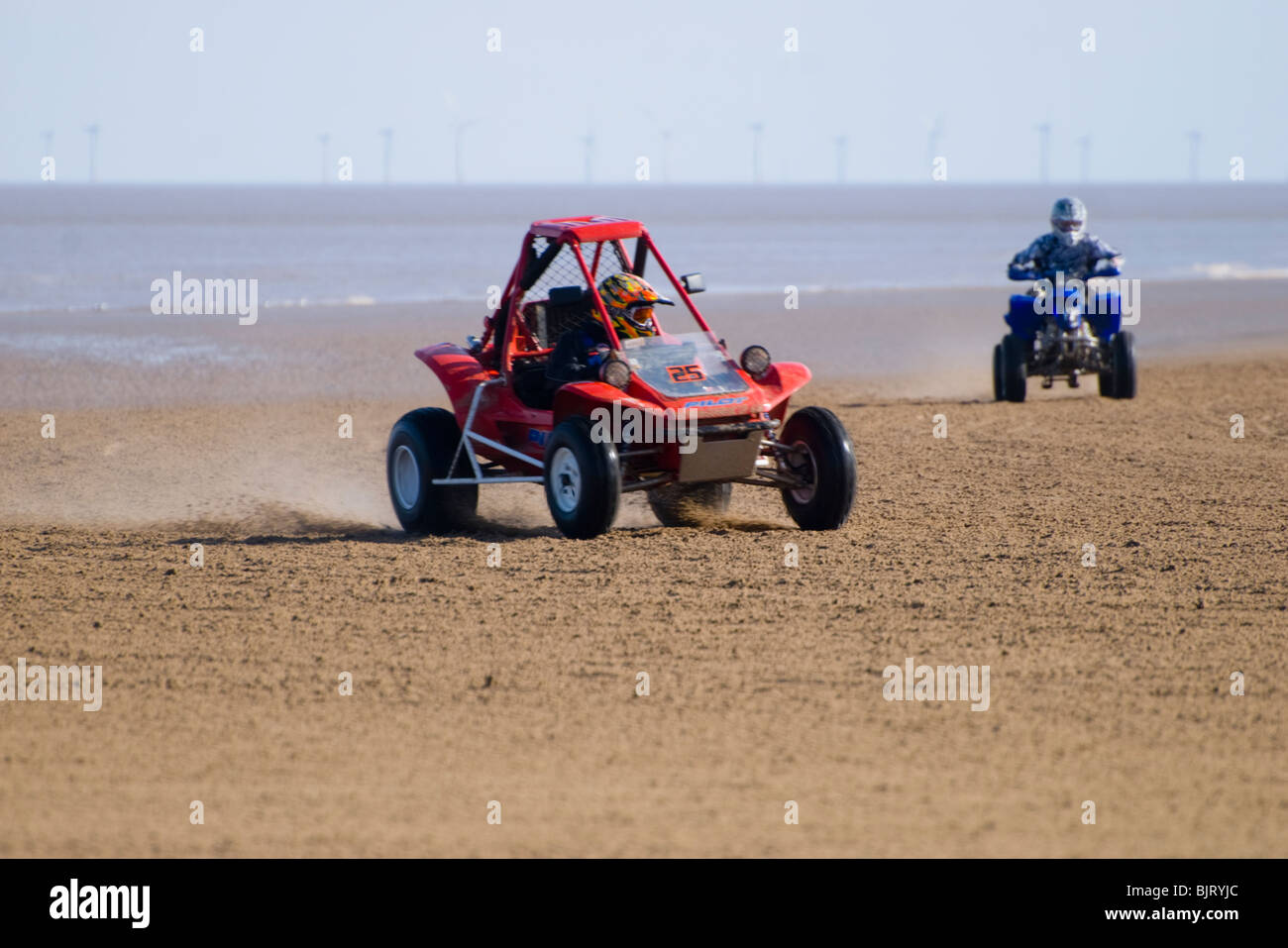 Quad bikes sand racing on the beach with wind turbines in the ...