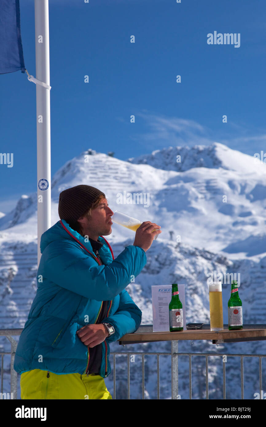 Skier enjoying drink of beer at Ice Bar Lech near St Saint Anton am Arlberg in winter snow Austrian Alps Austria Europe Stock Photo