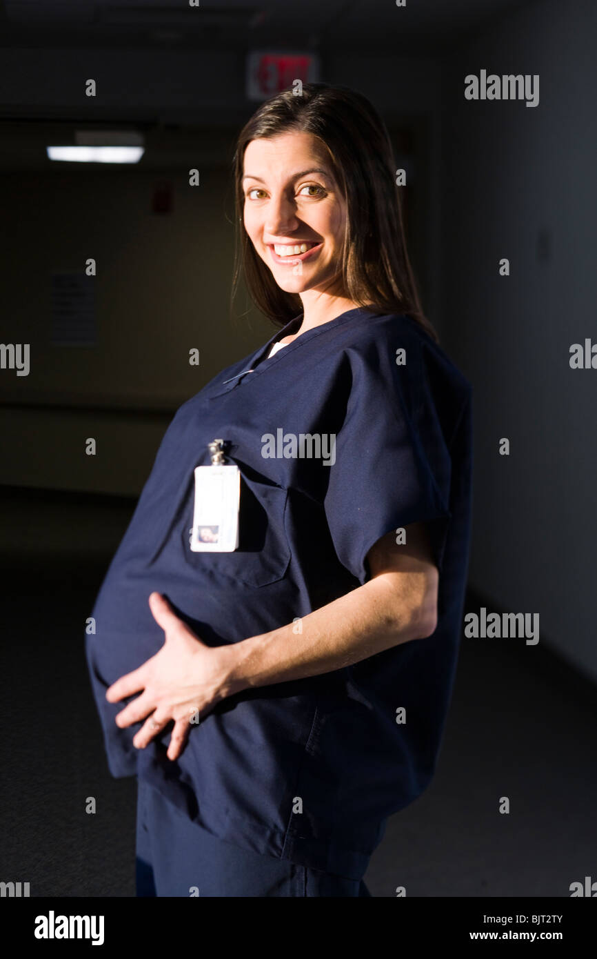 USA, Utah, Provo, female pregnant nurse smiling when touching her belly Stock Photo