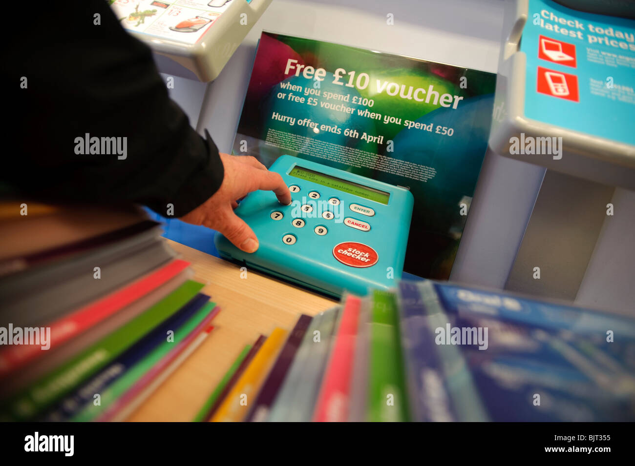 A Customer using the stock checker to choose items to buy at an Argos discount catalogue shop store UK Stock Photo