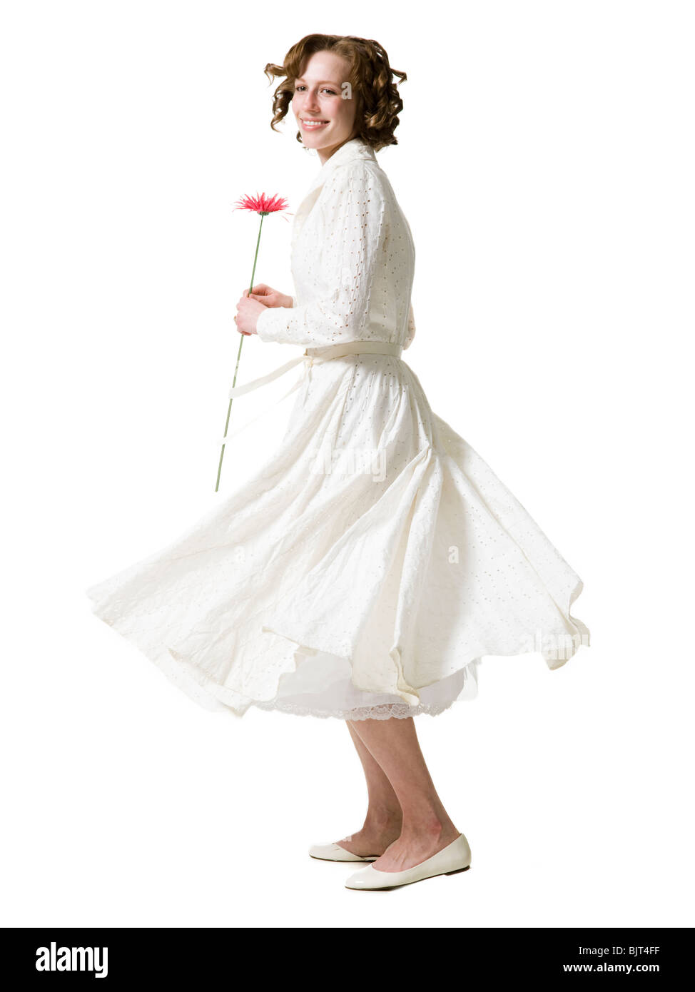 Happy young woman dancing with gerbera flower, portrait, studio shot Stock Photo