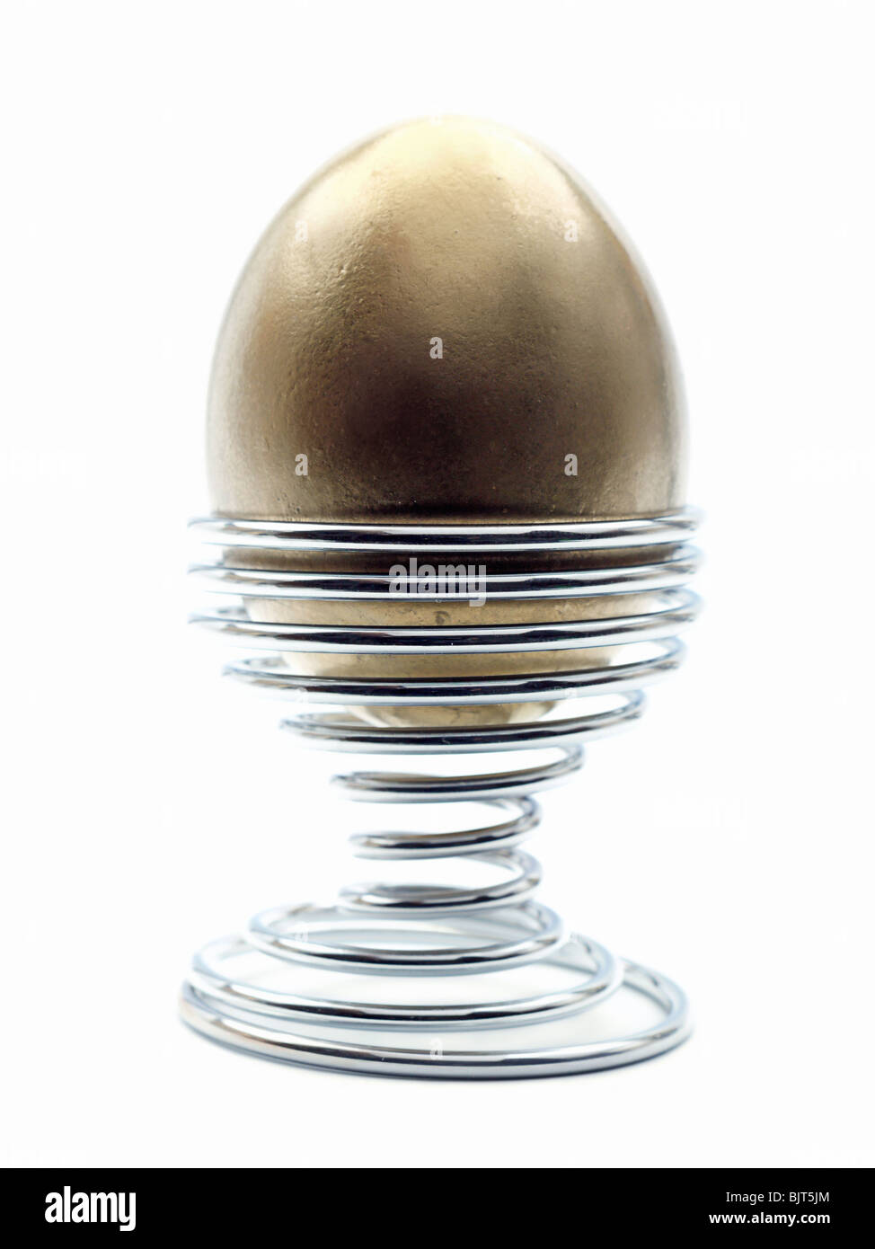 Golden egg in metal stand over white background Stock Photo