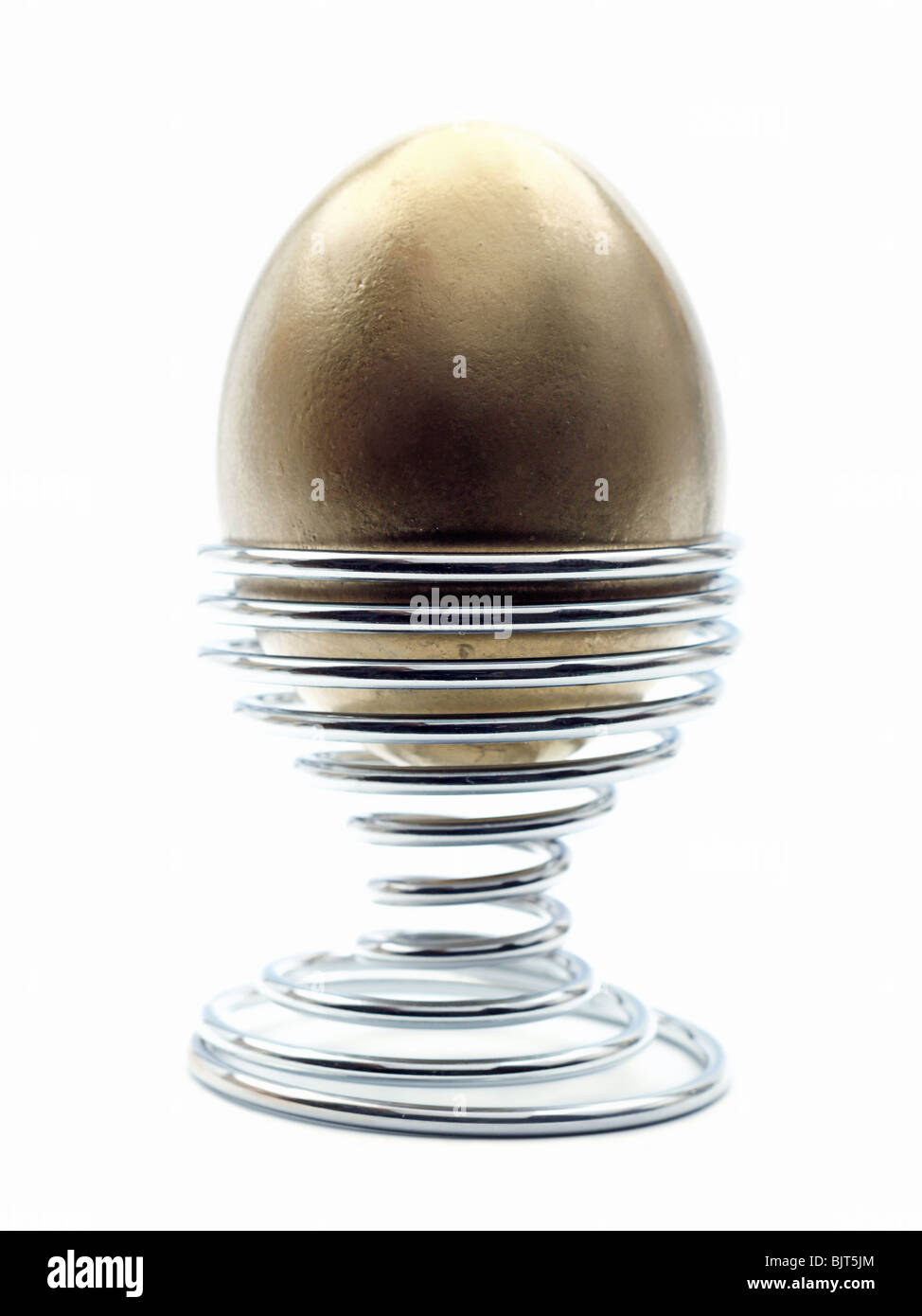 Golden egg in metal stand over white background Stock Photo Alamy