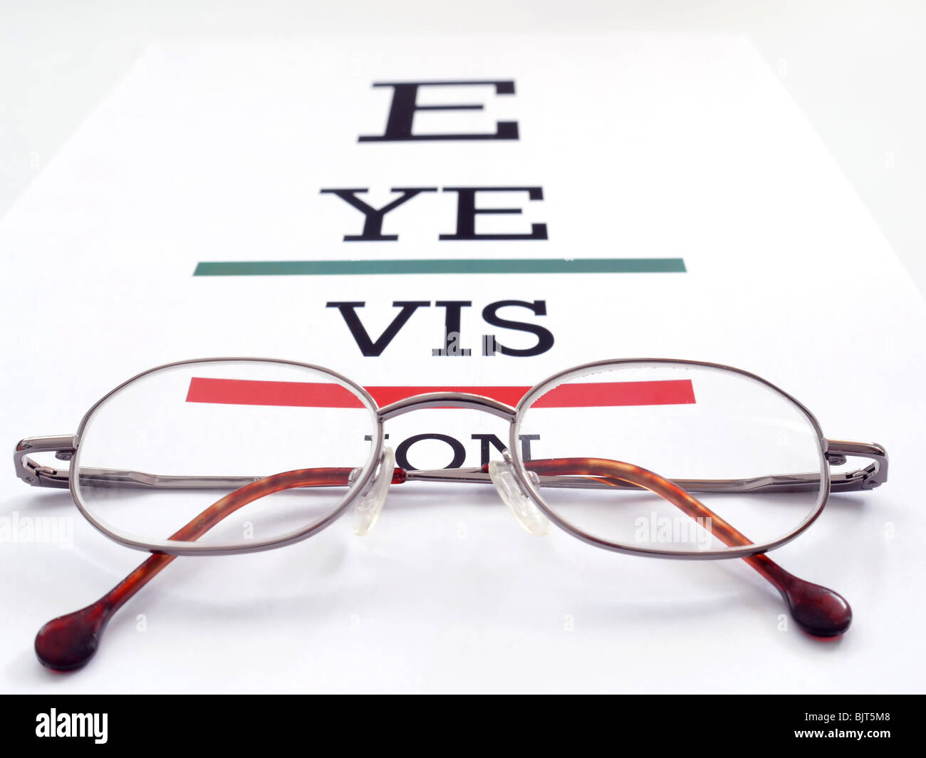 Eye glasses placed on conceptual eye exam chart spelling Eye Vision Stock Photo