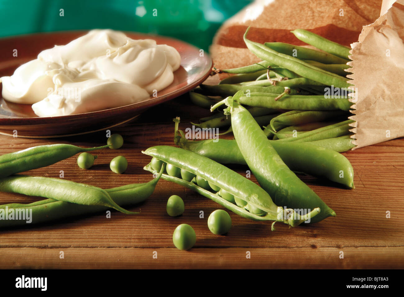 Food still life of fresh picked garden peas and pea in pods  on a rustic table in a kitchen being prepared Stock Photo
