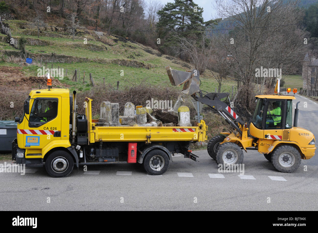 Old kilometre roadstone markers being ripped up and loaded into a lorry and removed. These signs are disappearing French icons. Stock Photo