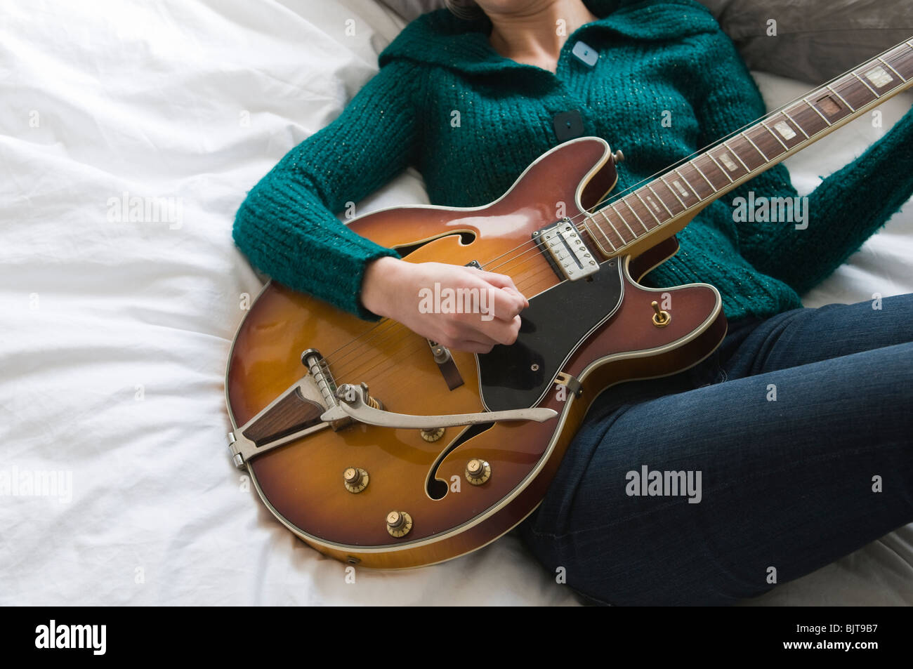 young woman playing guitar on bed Stock Photo Alamy