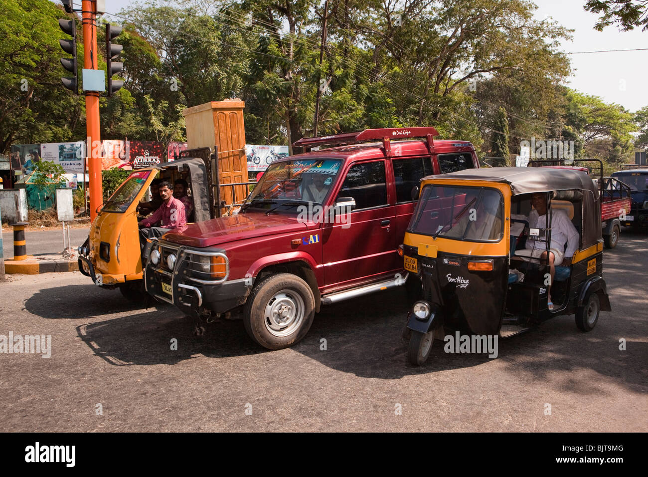 India, Kerala, Palakkad, road transport, autorickshaw, four wheel drive and three wheeler truck, waiting at traffic lights Stock Photo