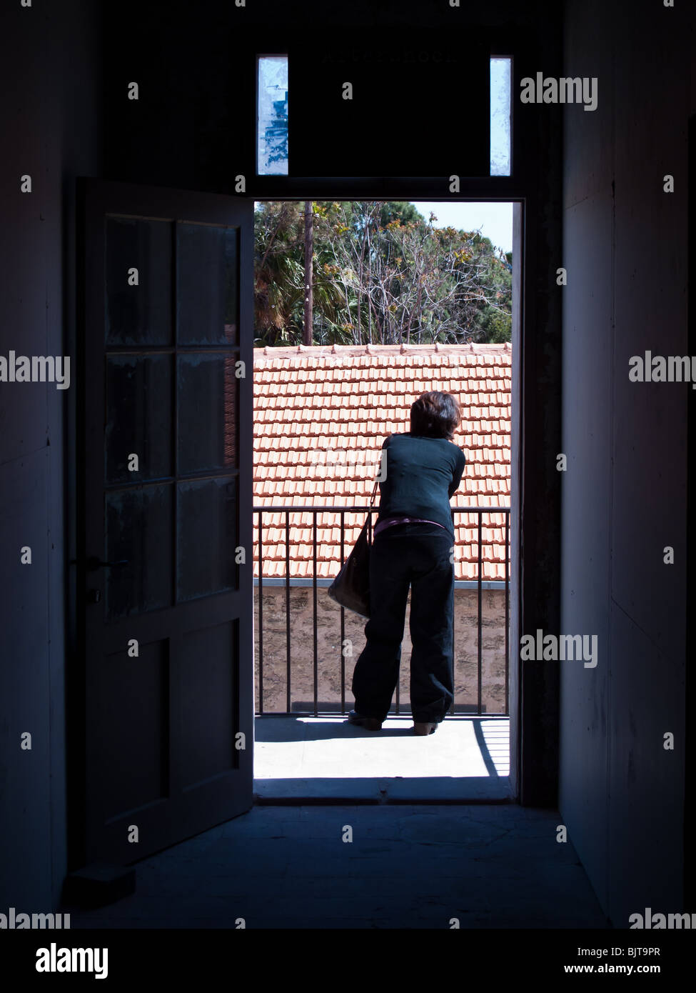 A woman from behind at the end of a dark hallway Stock Photo