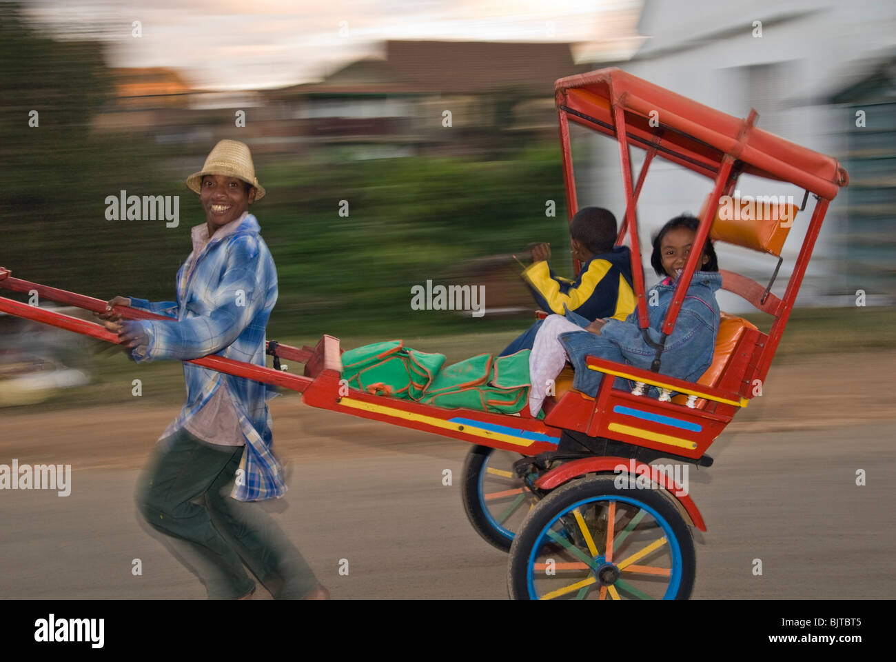 Rickshaw puller carrying passengers, Antsirabe, Madagascar Stock Photo