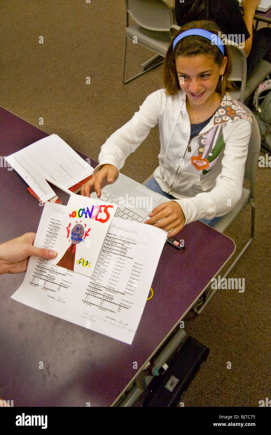 Sitting at her laptop computer in class, a happy California middle school student looks at an 'A' grade for her science paper. Stock Photo