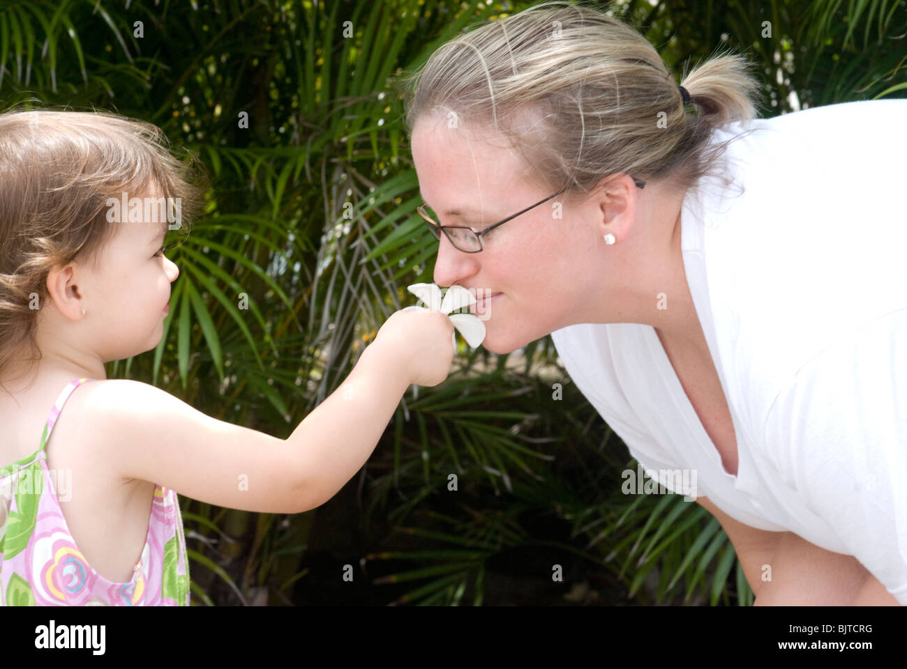 Mother and child having fun outdoors smelling a flower Stock Photo