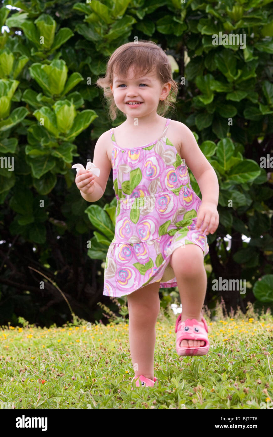 Two year old playful young girl having fun outdoors Stock Photo