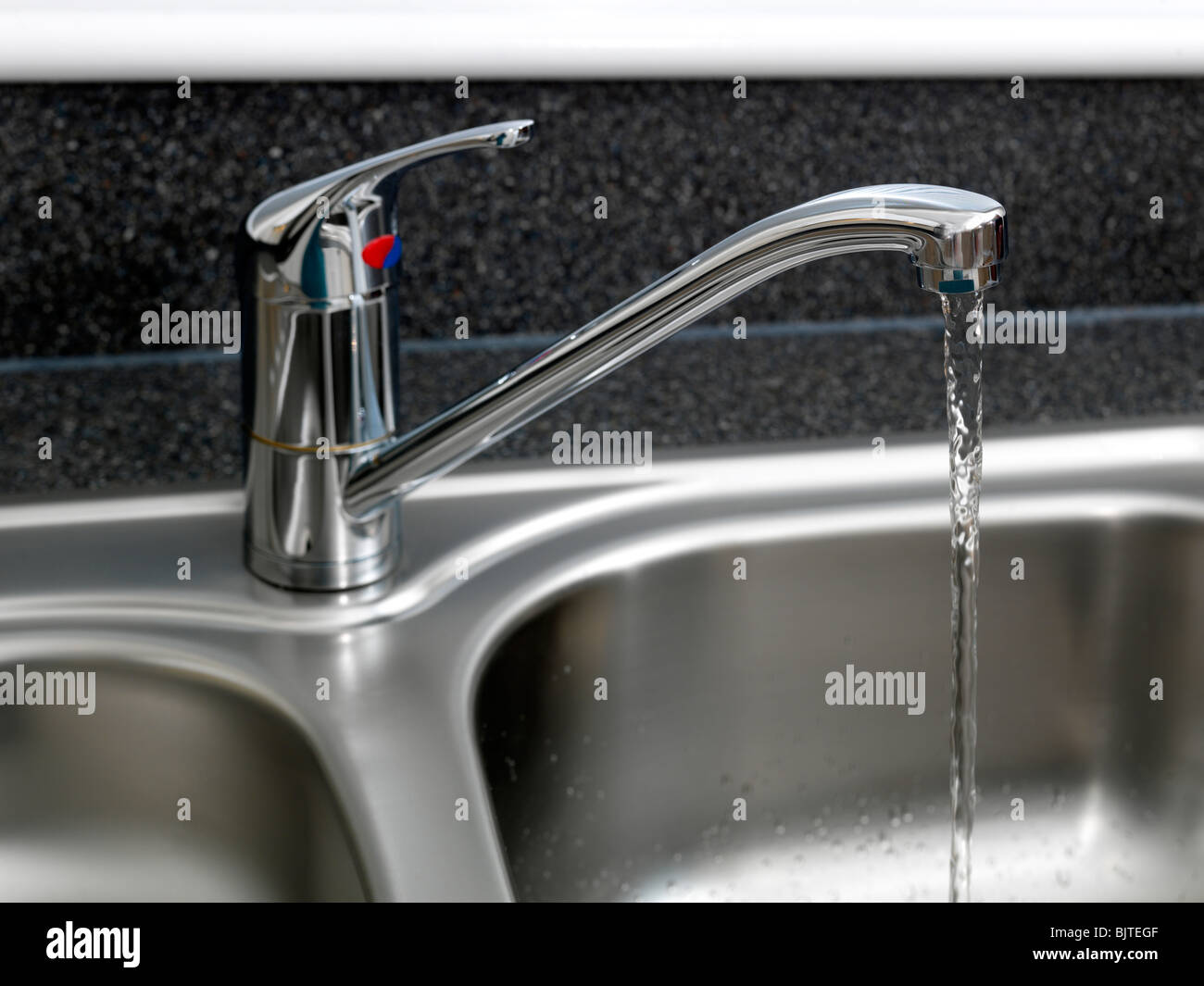 Water running From Tap In Kitchen Sink Stock Photo