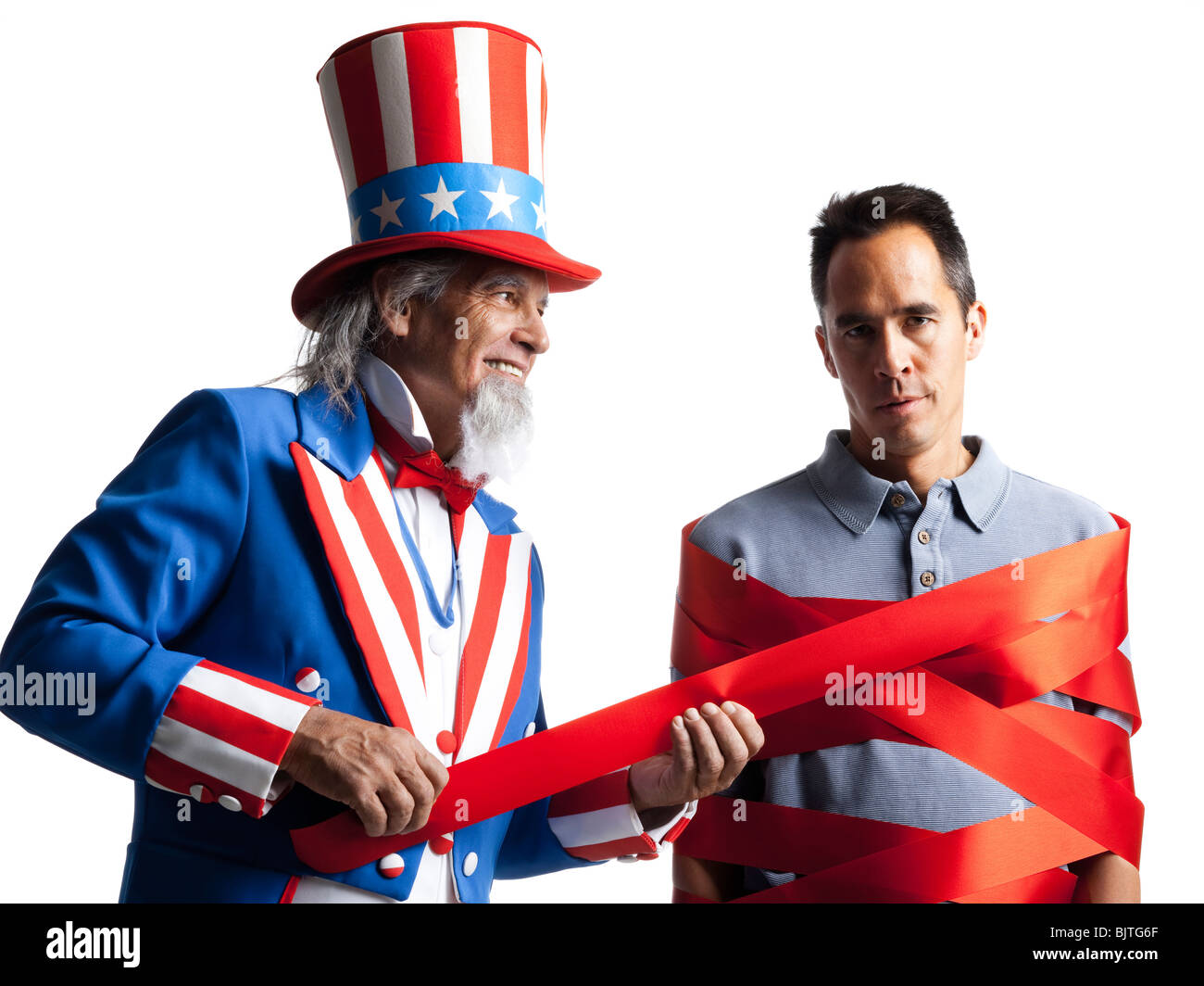 Man in Uncle Sam's costume wrapping other man with ribbon, studio shot Stock Photo