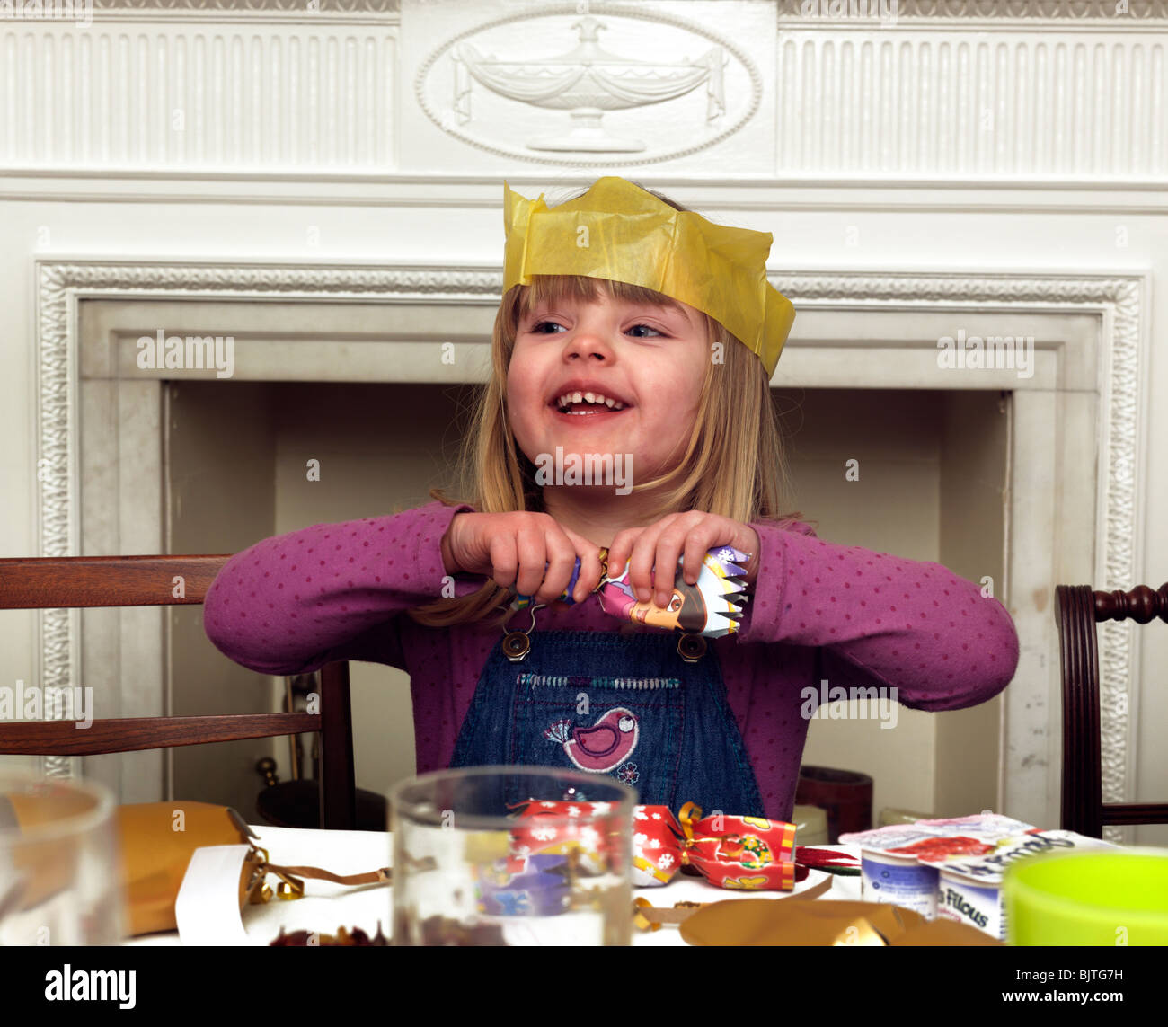 3 Year Old Girl Wearing A Christmas Hat And Pulling A Cracker England Stock Photo