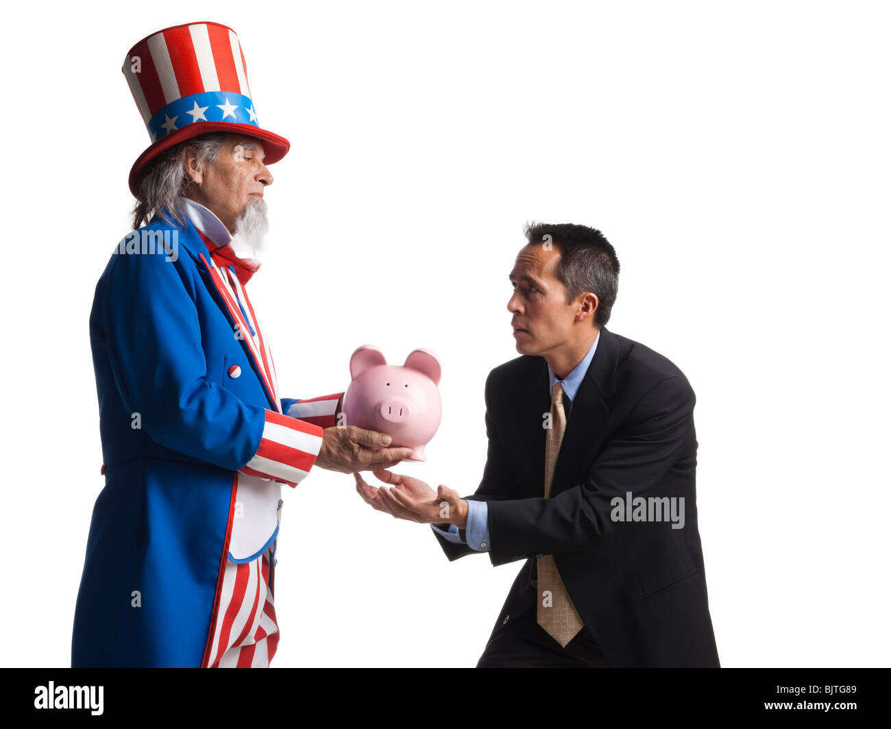 Man in Uncle Sam's costume giving piggybank to other man, studio shot Stock Photo