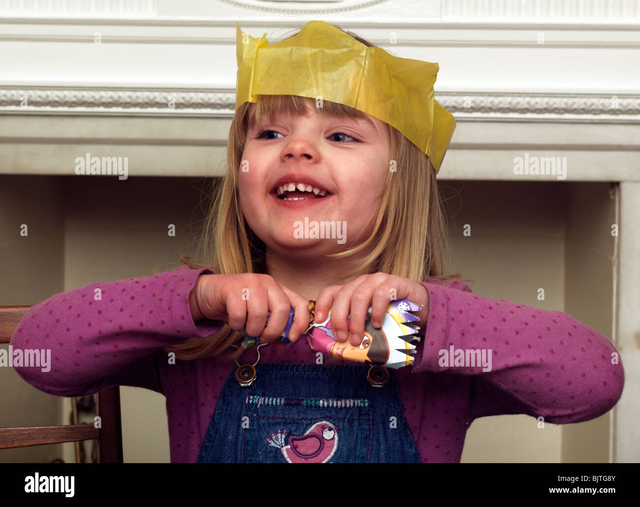 Three Year Old Girl Wearing A Christmas Hat Pulling a Cracker England Stock Photo