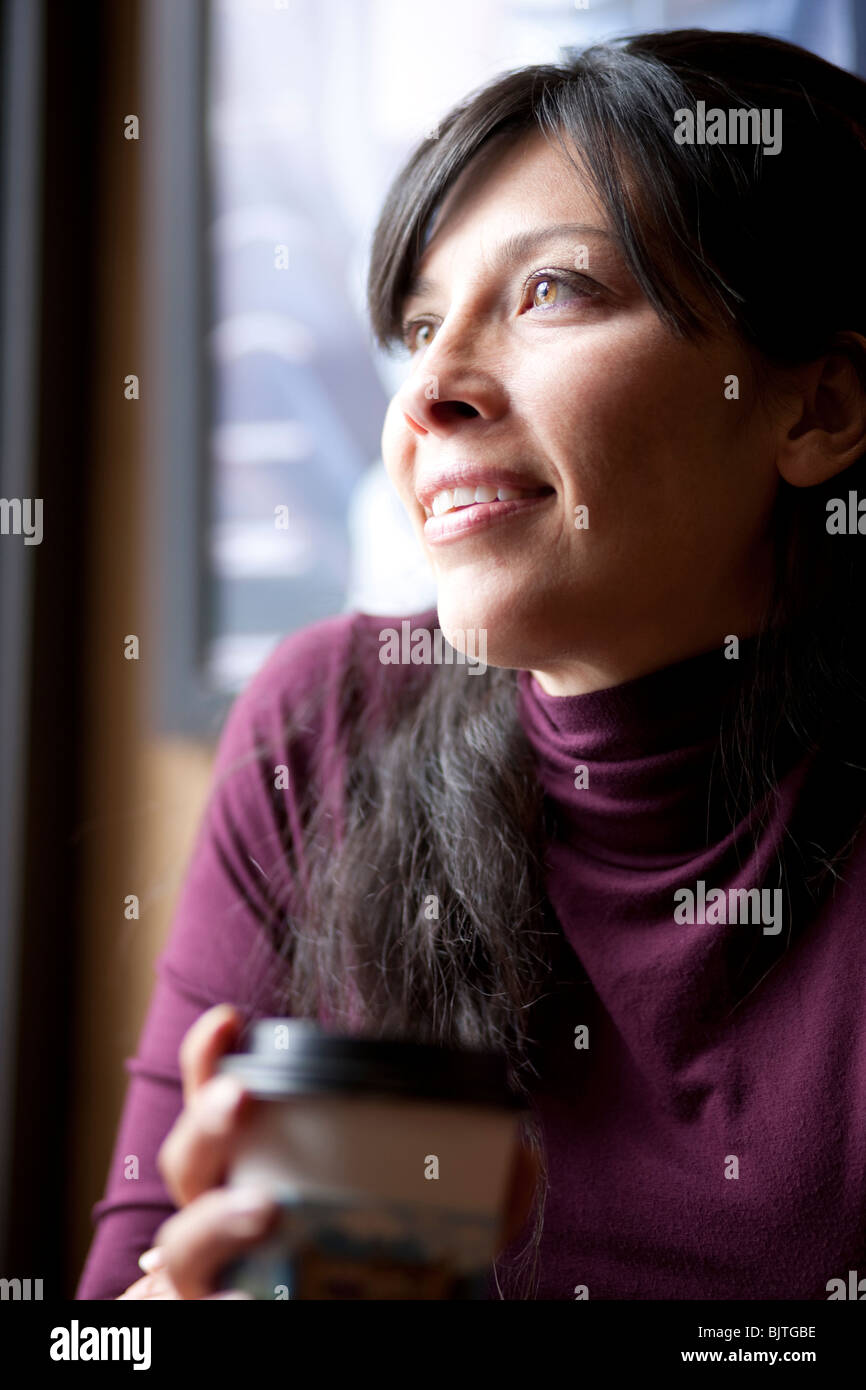 One mid adult woman drinking coffee in cafe Stock Photo