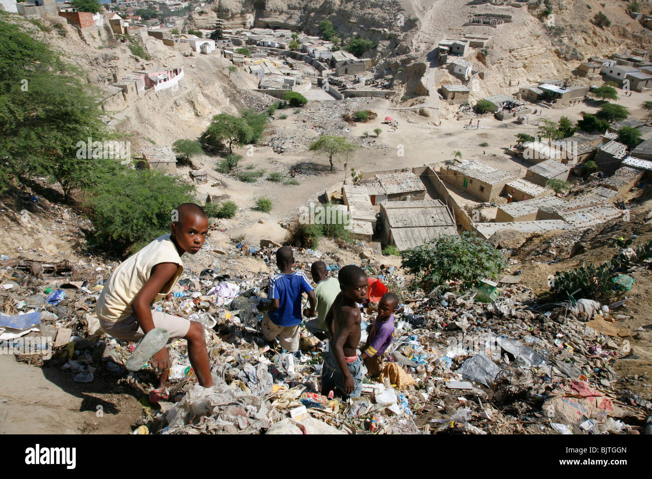 Children climbing down steep slope of rubbish just outside their home. Bairro area on the hills north of Lobito. Angola. Stock Photo