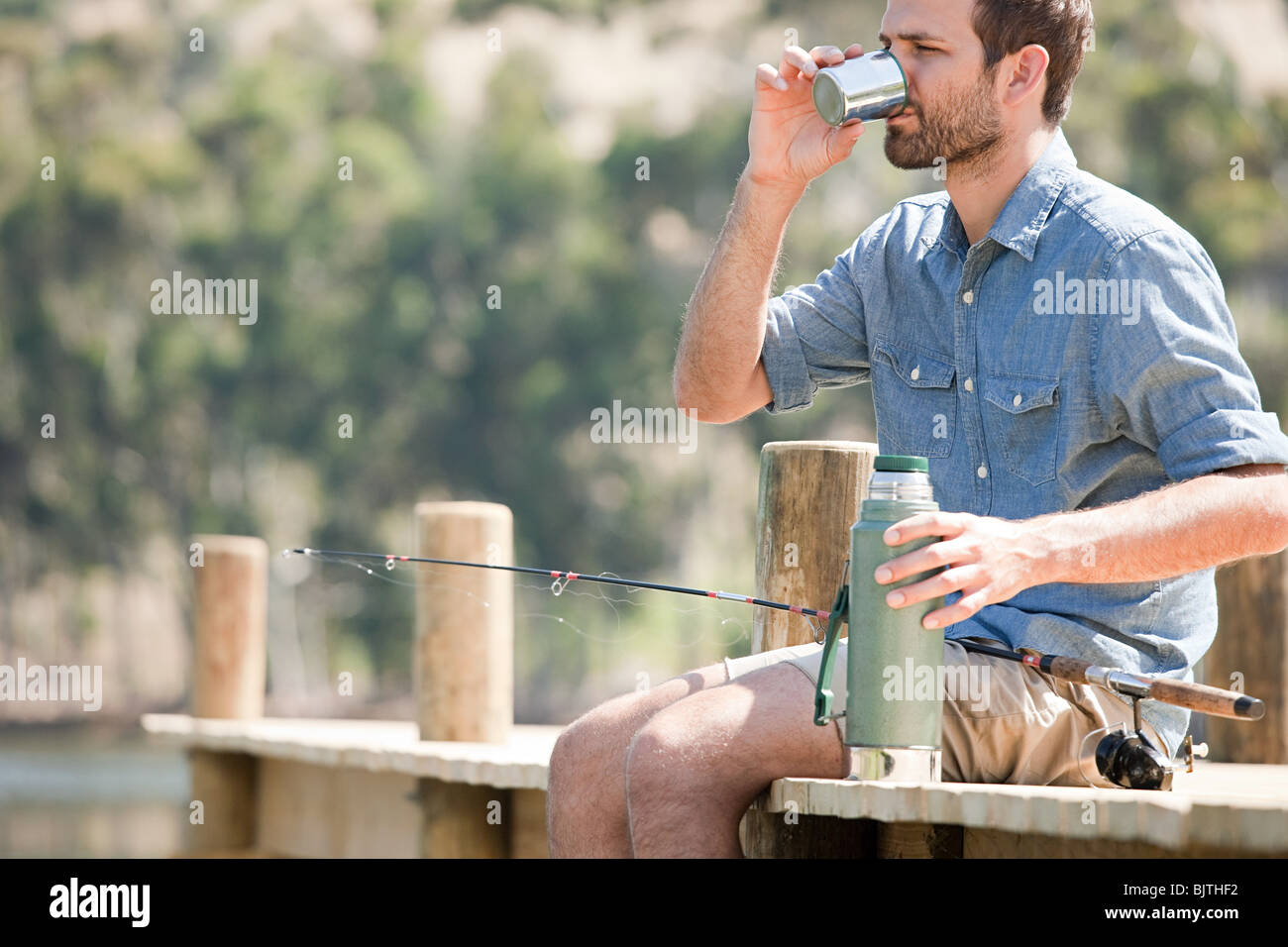 Man with fishing rod and hot drink Stock Photo