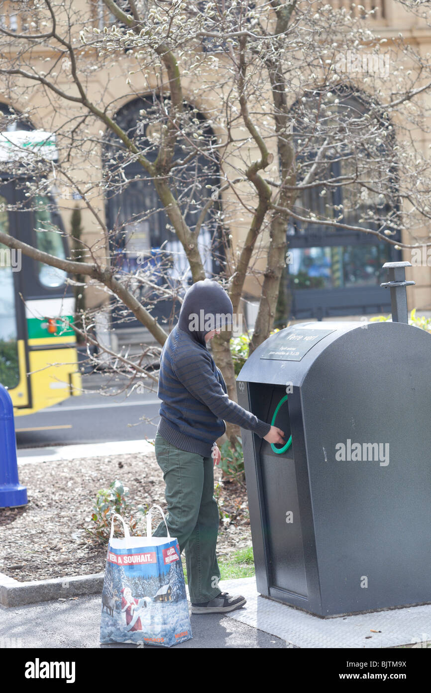 A 9 year old boy puts bottles in to a recycling bin, Switzerland. Charles Lupica Stock Photo