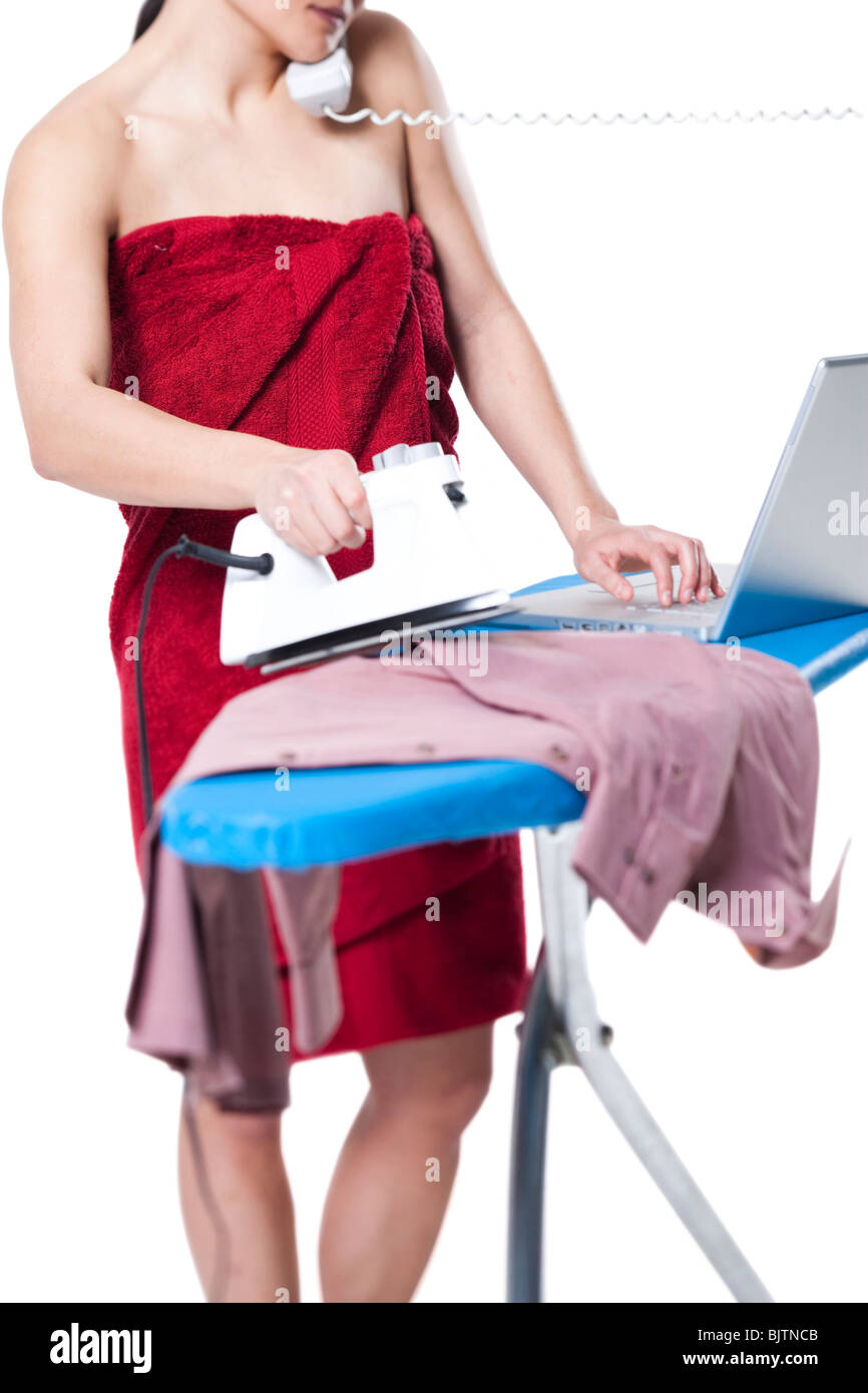 Woman ironing and working on laptop Stock Photo