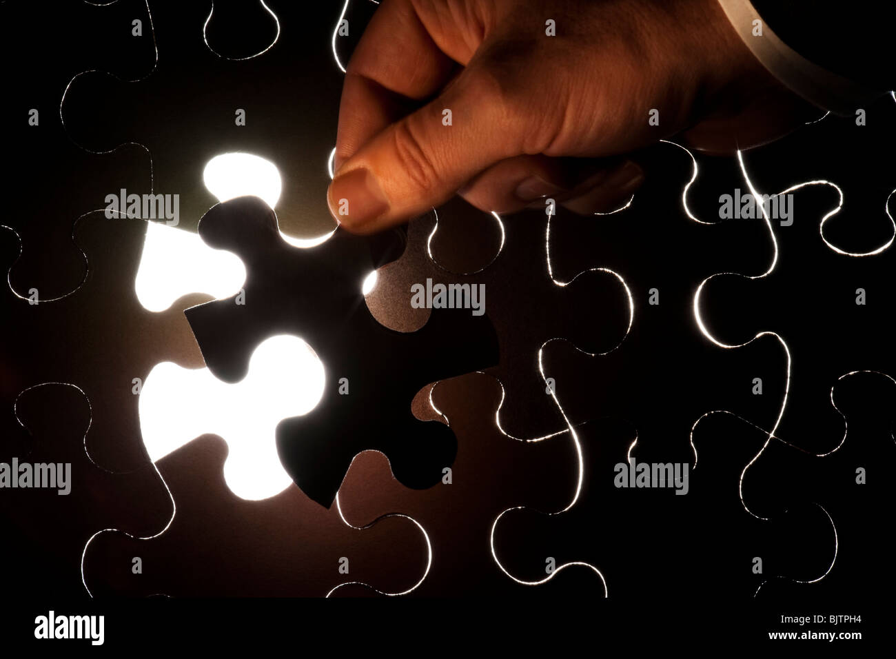 Hand inserting piece of jigsaw puzzle Stock Photo